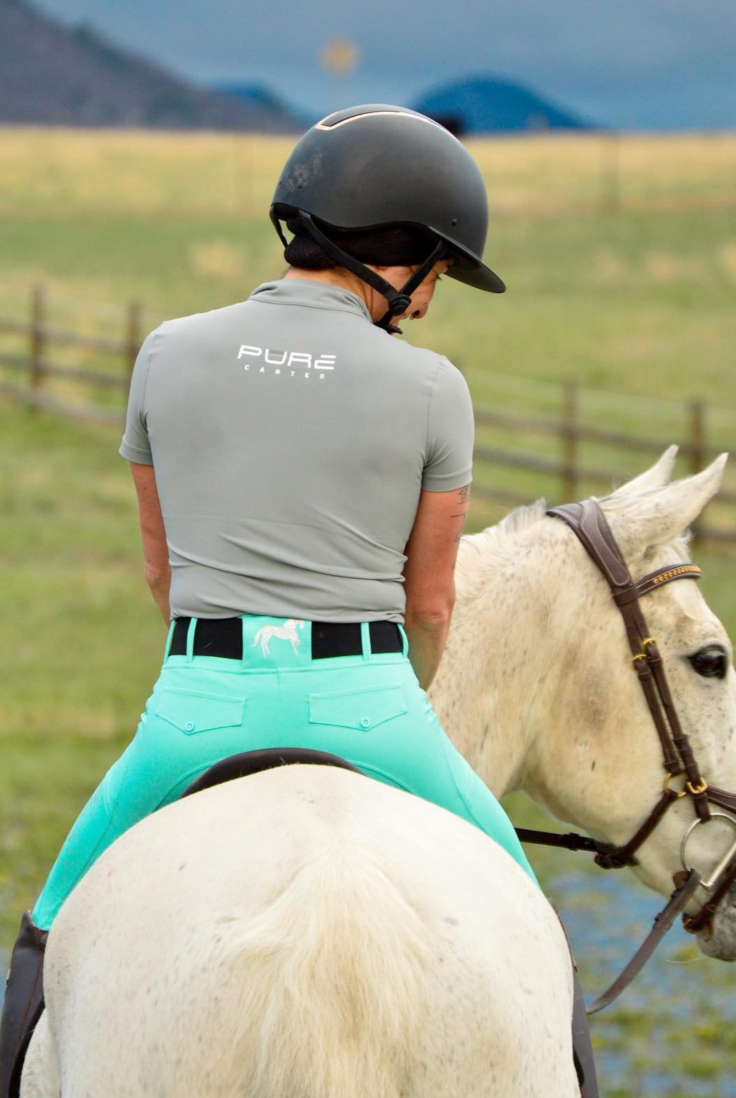 Girl on horseback enjoying her ride in a grey base layer by Pure Canter and aqua riding tights