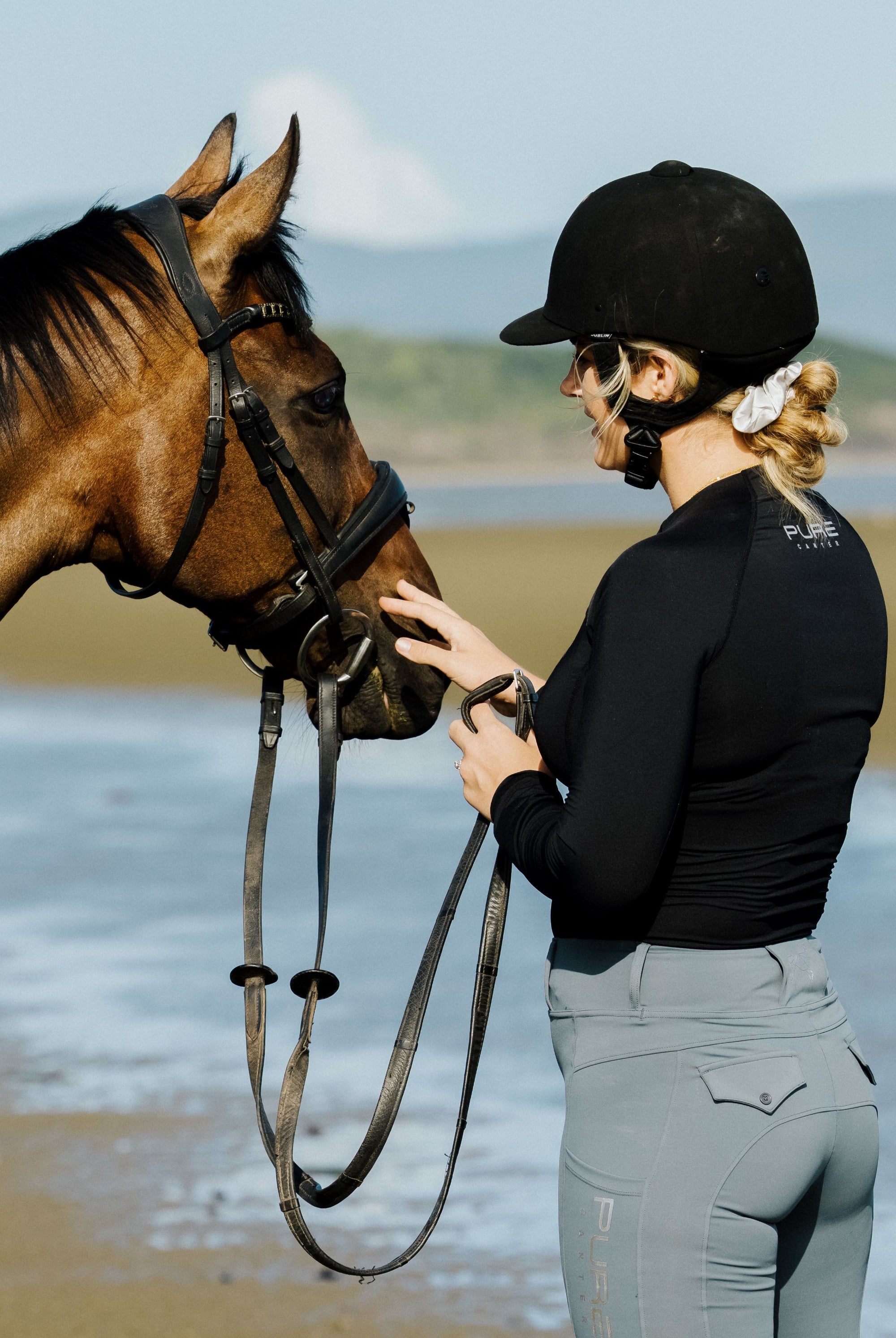 A close-up image of a rider wearing an equestrian base layer. The base layer is sleek and fitted, providing a comfortable and flexible foundation for riding attire.